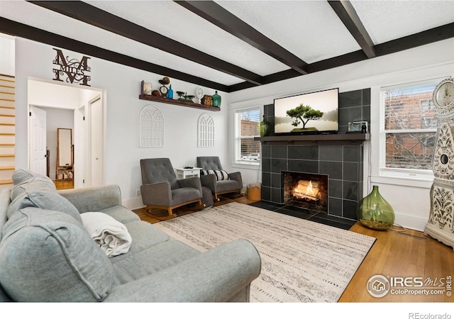 701 Mathews St, Fort Collins, CO 80524 - living area with a tile fireplace, beam ceiling, baseboards, wood finished floors, and stairs