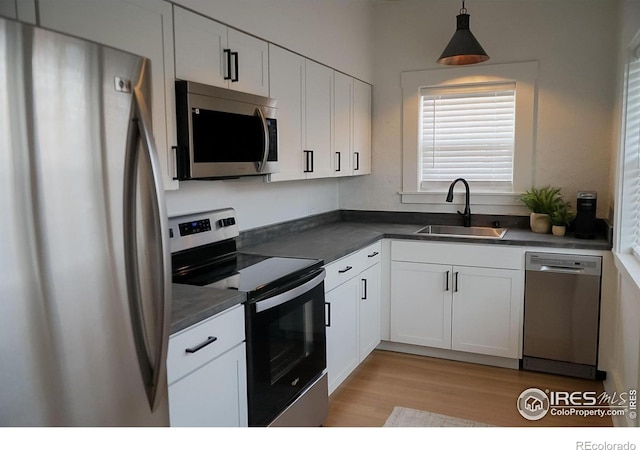 701 Mathews St, Fort Collins, CO 80524 - kitchen featuring stainless steel appliances, a sink, dark countertops, white cabinetry, and light wood-style flooring