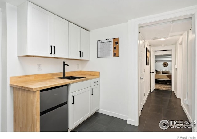 701 Mathews St, Fort Collins, CO 80524 - kitchen with a sink, butcher block countertops, baseboards, white cabinets, and dark tile patterned floors