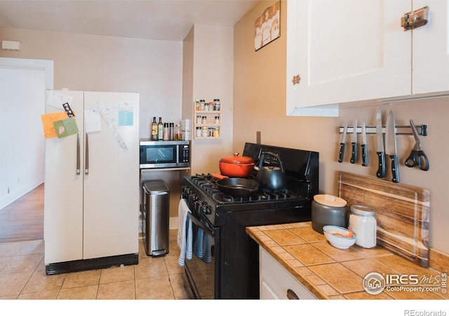 416 E Elizabeth St, Fort Collins, CO 80524 - kitchen featuring black gas range oven, freestanding refrigerator, stainless steel microwave, tile countertops, and white cabinets
