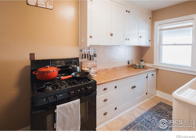 416 E Elizabeth St, Fort Collins, CO 80524 - kitchen featuring black range with gas cooktop, white cabinetry, light tile patterned floors, baseboards, and tile counters