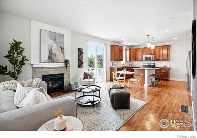 518 Hoyt Ln, Lafayette, CO 80026 - living area with light wood-style floors, a stone fireplace, recessed lighting, and baseboards