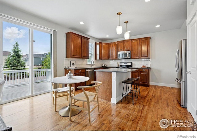 518 Hoyt Ln, Lafayette, CO 80026 - kitchen with stainless steel appliances, decorative backsplash, light wood-type flooring, a kitchen island, and decorative light fixtures