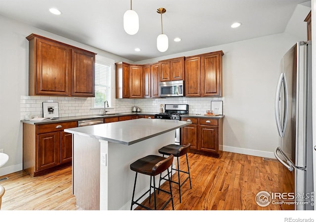 518 Hoyt Ln, Lafayette, CO 80026 - kitchen with appliances with stainless steel finishes, a sink, light wood-style floors, a kitchen bar, and recessed lighting