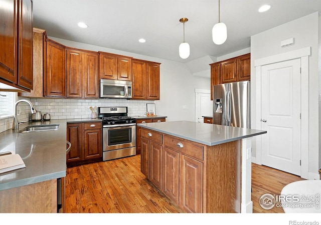 518 Hoyt Ln, Lafayette, CO 80026 - kitchen featuring appliances with stainless steel finishes, wood finished floors, decorative backsplash, a center island, and hanging light fixtures