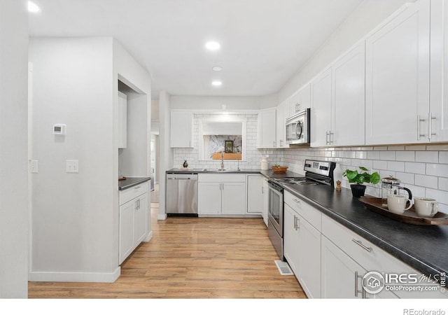 2836 W County Road 60e, Fort Collins, CO 80524 - kitchen featuring appliances with stainless steel finishes, a sink, light wood finished floors, white cabinets, and dark countertops