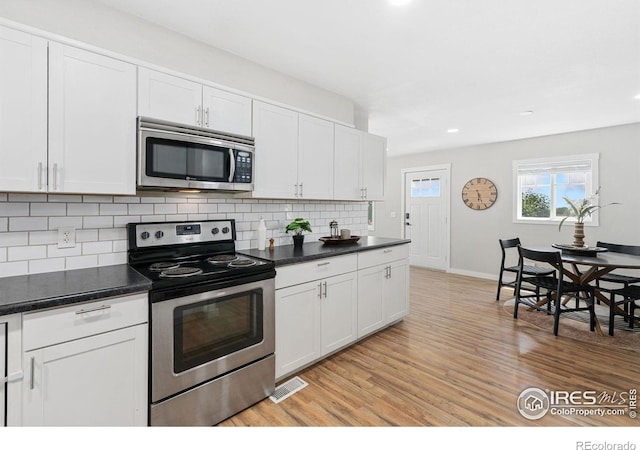 2836 W County Road 60e, Fort Collins, CO 80524 - kitchen with stainless steel appliances, light wood finished floors, dark countertops, decorative backsplash, and recessed lighting