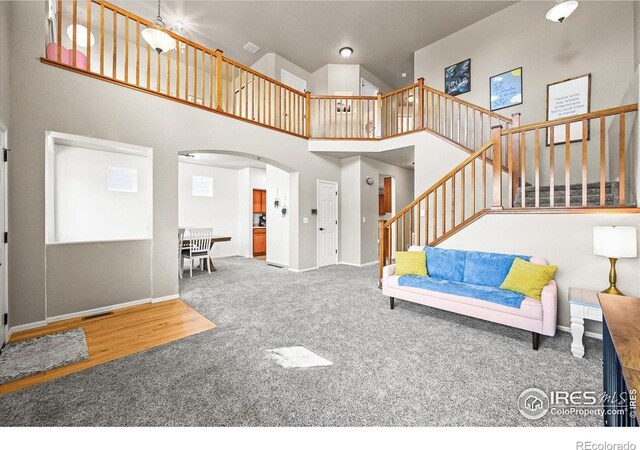 13445 Kearney St, Thornton, CO 80602 - carpeted living room with arched walkways, a towering ceiling, stairway, and baseboards