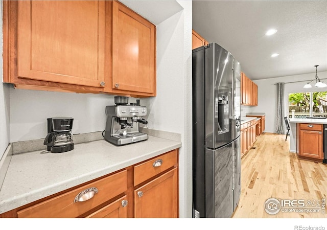 13445 Kearney St, Thornton, CO 80602 - kitchen with stainless steel fridge with ice dispenser, brown cabinetry, light countertops, light wood-style flooring, and recessed lighting