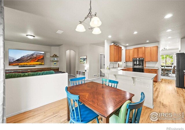 13445 Kearney St, Thornton, CO 80602 - dining space featuring arched walkways, light wood-style flooring, a chandelier, baseboards, and recessed lighting