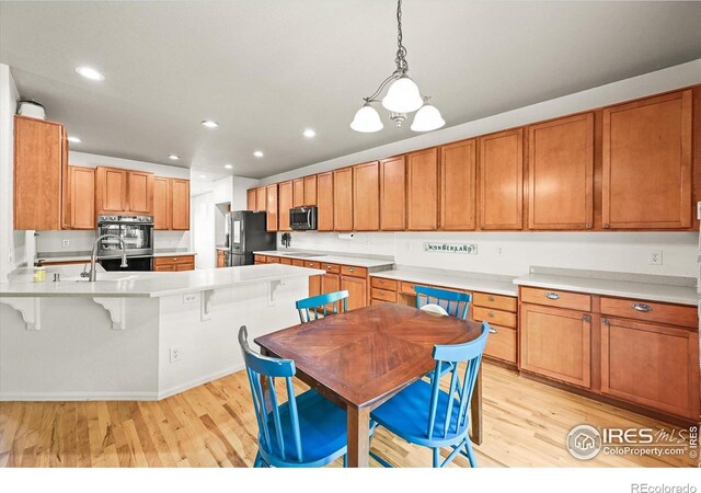 13445 Kearney St, Thornton, CO 80602 - kitchen featuring stainless steel appliances, light wood-style flooring, a peninsula, recessed lighting, and light countertops