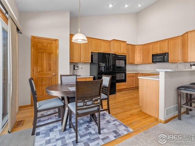 1536 Goshawk Dr, Longmont, CO 80504 - kitchen featuring high vaulted ceiling, black appliances, light countertops, decorative light fixtures, and a peninsula