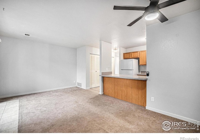 225 E 8th Ave Unit C-19, Longmont, CO 80504 - kitchen with freestanding refrigerator, ceiling fan, carpet, baseboards, and brown cabinetry