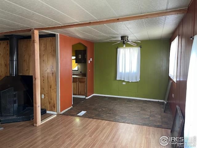 4809 Foothills Dr, Fort Collins, CO 80526 - unfurnished living room featuring wood finished floors, a ceiling fan, a wood stove, baseboards, and arched walkways