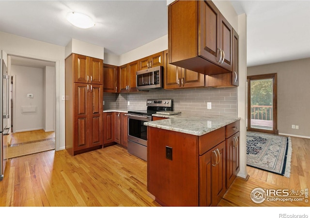 1409 Welch St, Fort Collins, CO 80524 - kitchen featuring appliances with stainless steel finishes, light wood-style floors, tasteful backsplash, brown cabinetry, and light stone counters