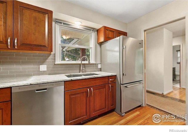 1409 Welch St, Fort Collins, CO 80524 - kitchen featuring appliances with stainless steel finishes, a sink, light wood finished floors, tasteful backsplash, and brown cabinets