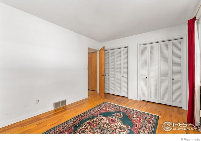 1409 Welch St, Fort Collins, CO 80524 - unfurnished bedroom featuring multiple closets, hardwood / wood-style flooring, and baseboards
