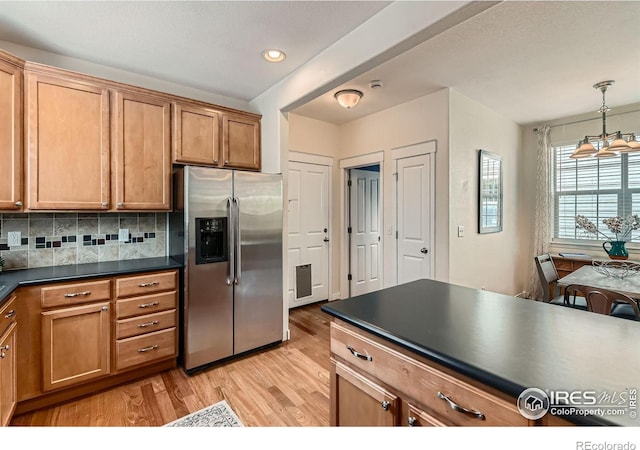 634 Homestead St, Lafayette, CO 80026 - kitchen with stainless steel fridge, light wood finished floors, dark countertops, tasteful backsplash, and pendant lighting