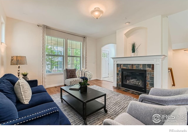 634 Homestead St, Lafayette, CO 80026 - living area featuring arched walkways, wood finished floors, a tile fireplace, and baseboards