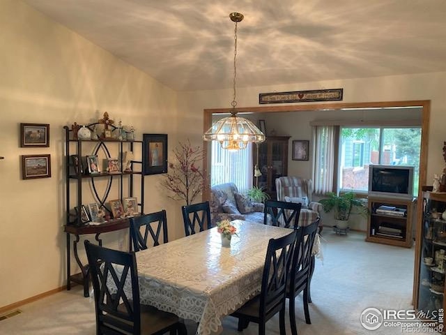 1515 Tulip Ct, Longmont, CO 80501 - dining room with a chandelier, light colored carpet, vaulted ceiling, and baseboards