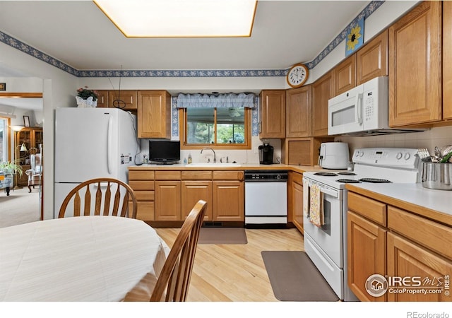 1515 Tulip Ct, Longmont, CO 80501 - kitchen with white appliances, a sink, light wood finished floors, light countertops, and tasteful backsplash