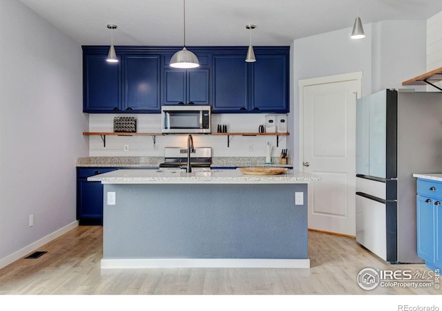 3657 Speedwell St, Wellington, CO 80549 - kitchen with blue cabinets, appliances with stainless steel finishes, open shelves, light wood finished floors, and an island with sink
