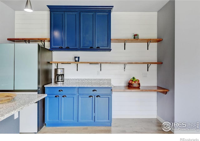 3657 Speedwell St, Wellington, CO 80549 - kitchen with open shelves, blue cabinetry, and freestanding refrigerator