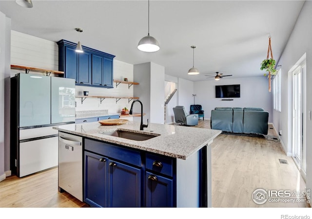 3657 Speedwell St, Wellington, CO 80549 - kitchen with stainless steel dishwasher, blue cabinetry, freestanding refrigerator, and light wood-style flooring
