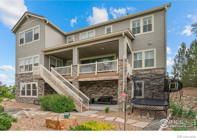 3075 Blue Mountain Dr, Broomfield, CO 80023 - rear view of house featuring a trampoline, stone siding, stairs, a patio area, and covered porch