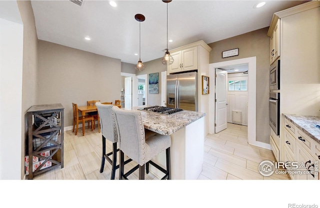 904 N Jefferson Ave, Loveland, CO 80537 - kitchen with appliances with stainless steel finishes, a kitchen island, light stone counters, a breakfast bar area, and baseboards