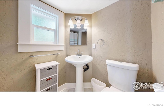 904 N Jefferson Ave, Loveland, CO 80537 - bathroom with toilet, a sink, and a chandelier