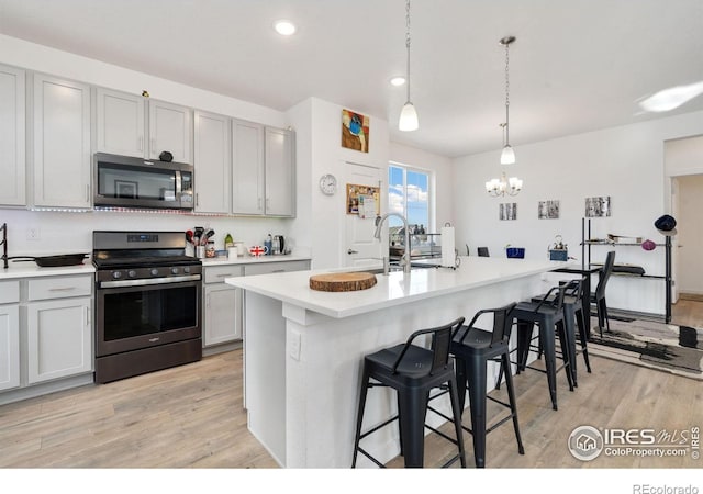1958 Autumn Moon Dr, Windsor, CO 80550 - kitchen featuring appliances with stainless steel finishes, a chandelier, a kitchen bar, light wood finished floors, and recessed lighting