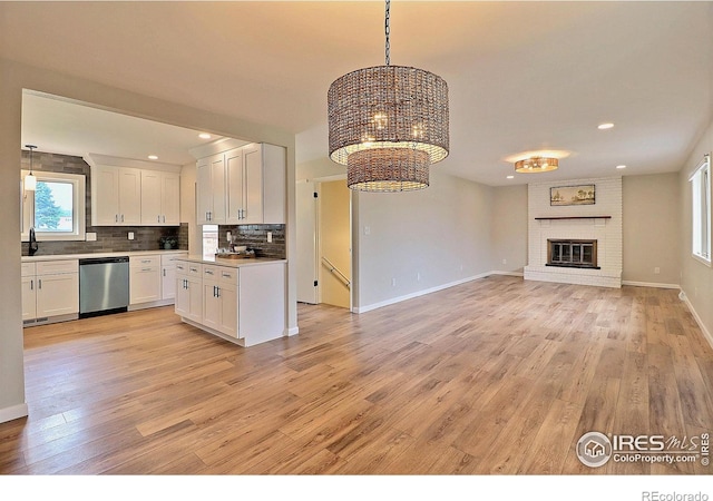 2217 14th St, Greeley, CO 80631 - kitchen with dishwasher, open floor plan, white cabinetry, a chandelier, and light wood-style floors