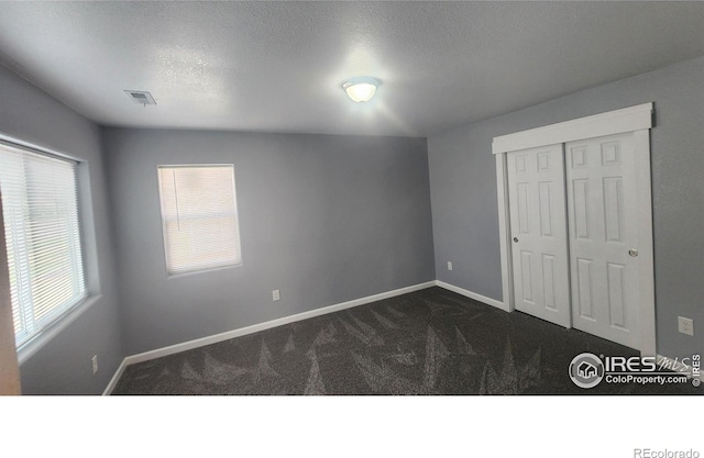 222 Platte St, Sterling, CO 80751 - unfurnished bedroom featuring dark colored carpet, baseboards, a closet, and a textured ceiling