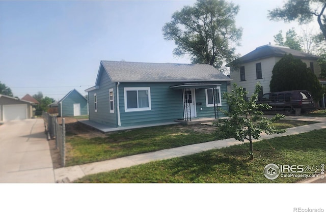 222 Platte St, Sterling, CO 80751 - view of front of house featuring a front yard, a shingled roof, an outdoor structure, and concrete driveway