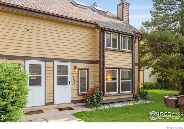 985 W 10th St Unit A5, Loveland, CO 80537 - back of house featuring a chimney, a yard, and roof with shingles