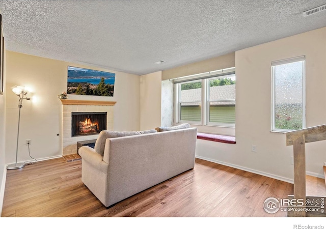 985 W 10th St Unit A5, Loveland, CO 80537 - living room featuring a brick fireplace, light wood-style flooring, plenty of natural light, and a textured ceiling