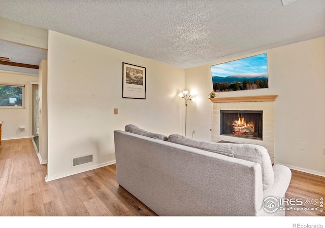 985 W 10th St Unit A5, Loveland, CO 80537 - living room featuring wood finished floors, a lit fireplace, a textured ceiling, and baseboards