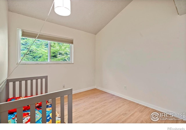 985 W 10th St Unit A5, Loveland, CO 80537 - unfurnished bedroom featuring wood finished floors, baseboards, and lofted ceiling