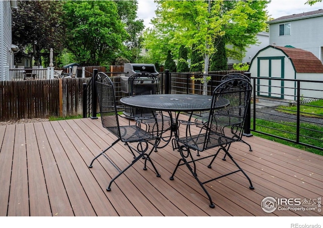 1309 Red Mountain Dr, Longmont, CO 80504 - deck with outdoor dining space, a storage unit, and a fenced backyard