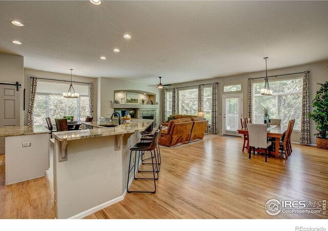 6208 Treestead Ct, Fort Collins, CO 80528 - kitchen featuring a chandelier, light wood finished floors, recessed lighting, ceiling fan, and a kitchen bar