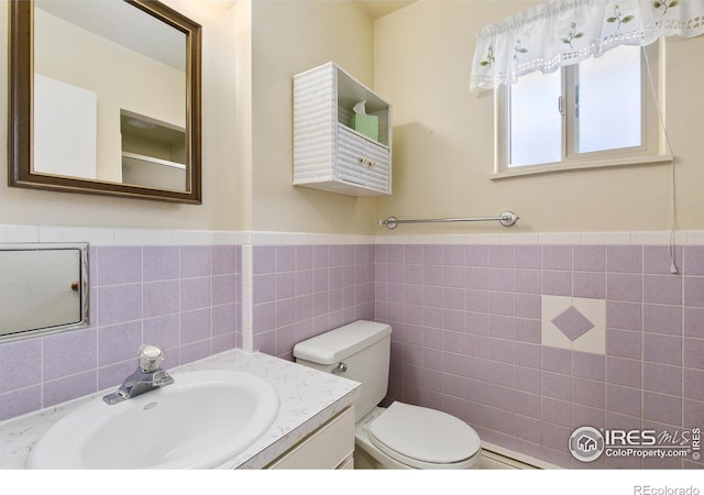 1204 Newsom St, Fort Collins, CO 80524 - half bathroom with tile walls, toilet, vanity, and a wainscoted wall