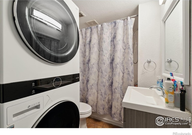 6743 King St, Denver, CO 80221 - bathroom featuring stacked washer / dryer, tile patterned flooring, toilet, vanity, and a textured ceiling