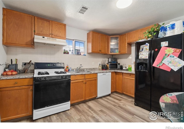 6743 King St, Denver, CO 80221 - kitchen with range with gas stovetop, dishwasher, black fridge, under cabinet range hood, and stainless steel microwave