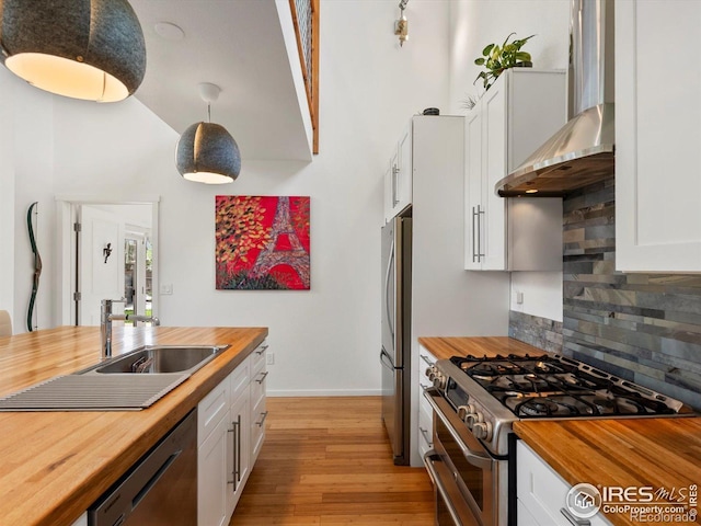 404 W Cleveland St, Lafayette, CO 80026 - kitchen featuring wooden counters, stainless steel appliances, wall chimney range hood, decorative backsplash, and light wood-style floors