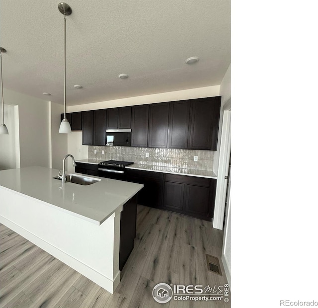 6113 Zebulon Pl, Timnath, CO 80547 - kitchen with a sink, gas stove, backsplash, light wood-style flooring, and a textured ceiling