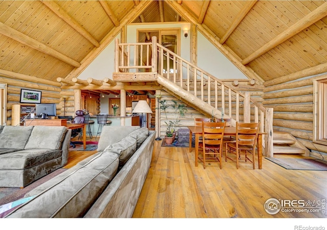 114 Jade Way, Lyons, CO 80540 - living room with log walls, high vaulted ceiling, wood ceiling with exposed beams, stairway, and hardwood / wood-style flooring