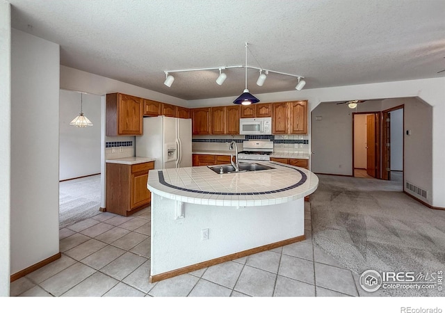 678 Mcclure Ct, Erie, CO 80516 - kitchen featuring white appliances, a sink, light tile patterned floors, brown cabinets, and a textured ceiling