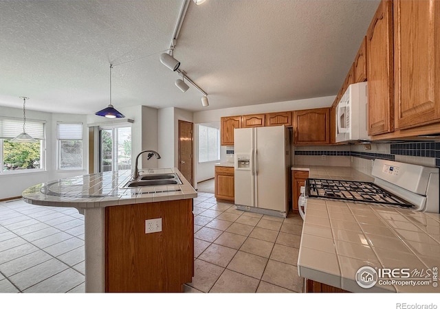 678 Mcclure Ct, Erie, CO 80516 - kitchen featuring white appliances, a sink, tile counters, rail lighting, and a textured ceiling