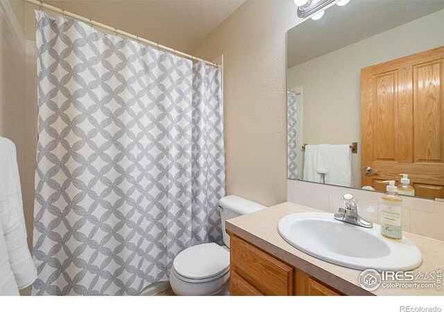 1502 Westfield Dr, Fort Collins, CO 80526 - full bathroom featuring vanity, toilet, tasteful backsplash, a textured wall, and curtained shower
